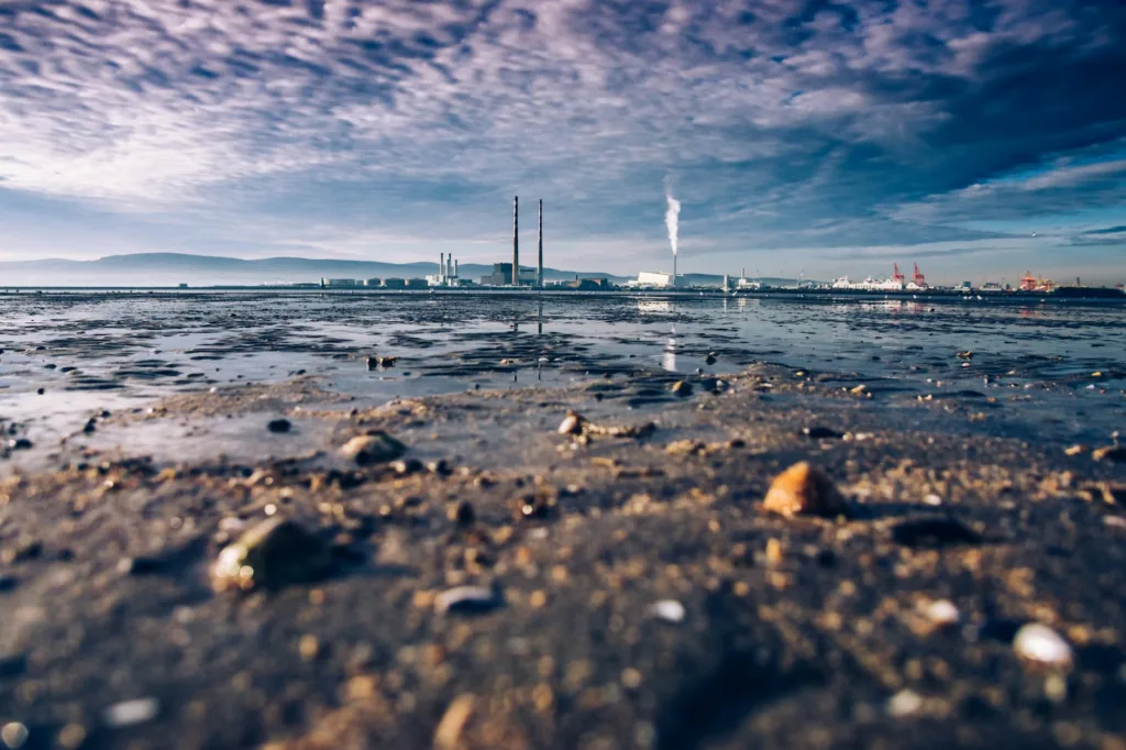 MARPOL: Sejarah dan Peran Pentingnya dalam Melindungi Lautan Kita 3 View of Dublin Bay with chimneys and industrial plant, reflecting on calm waters under a cloudy sky.
