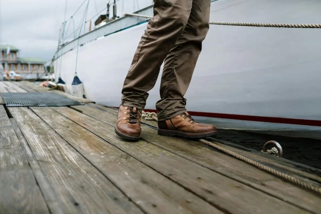 Mengenal STCW: Standar Pelatihan dan Sertifikasi untuk Pelaut 5 Brown leather boots on a wooden dock next to a boat, showcasing a rugged outdoor style.